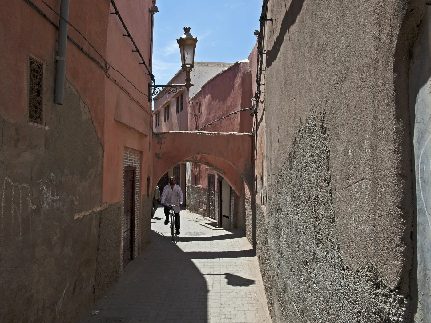 Shaded alley in the Marrakech medina with ochre walls and a wooden door