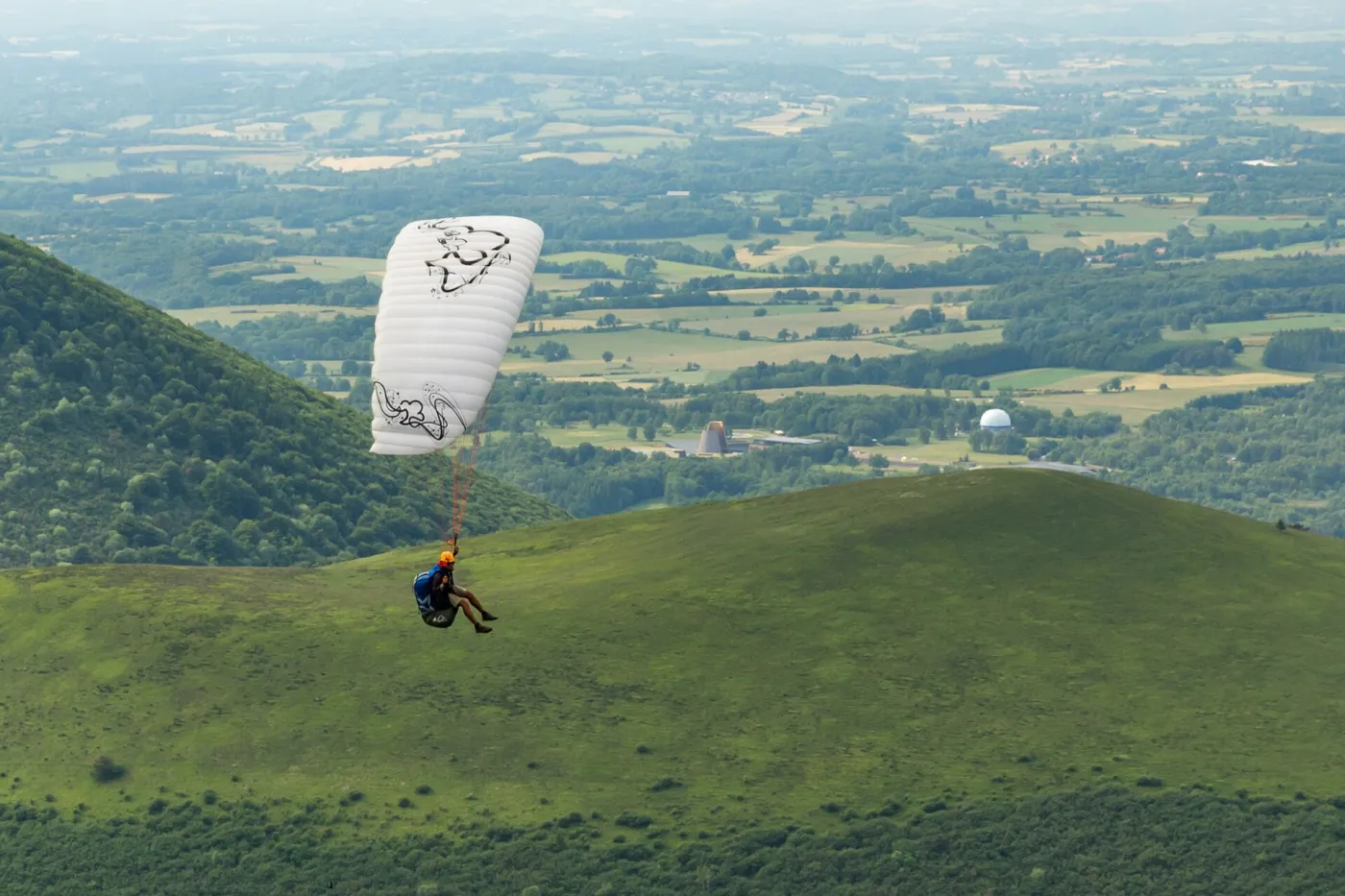 Paraglider above green hills